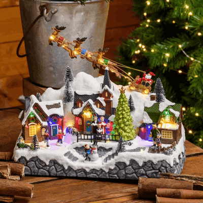 Paesaggio natalizio con Babbo Natale su slitta volante e pattinatori in movimento, led multicolor