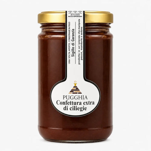 Un barattolo di vetro con confettura extra di ciliegie puggghia con coperchio dorato ed etichetta bianca testo nero