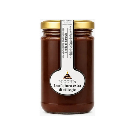 Un barattolo di vetro con confettura extra di ciliegie puggghia da 300 gr con tappo dorato ed etichetta bianca