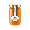Un barattolo di vetro con coperchio dorato contenente miele puggghia extra con etichetta bianca elegante per confettura di percoche da 300 gr