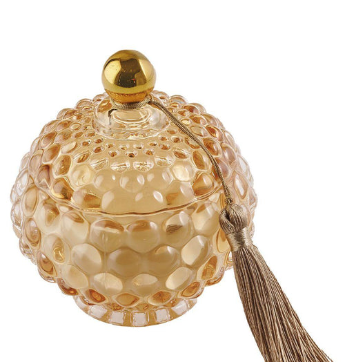 Candela in vetro ambra con forma bon bon e nappina decorativa, firmata Special Gifts, altezza 11 cm, diametro 8 cm, con scatola regalo.